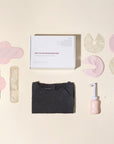 Overzicht van Essentuary postpartum essentials in de Ode to Motherhood Box, met de Peri Bottle, bostkompressen, kraamverband en de bevallingsjurk